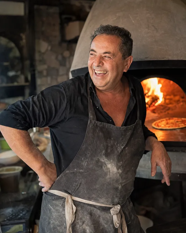 A pizzeria owner by his wood-fired oven